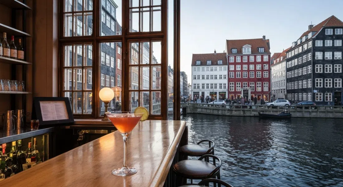 Ruby-Cocktailbar in einem Stadthaus aus dem 18. Jahrhundert in der Nybrogade 10, warmes Abendlicht durch die Fenster und ein klassischer Cocktail an der Bar mit Blick auf den Kanal